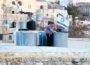 An Israeli settler puts an Israeli flag on the roof of a Palestinian house in a building in the center of the Palestinian city Hebron. (Photo: Via MEMO)